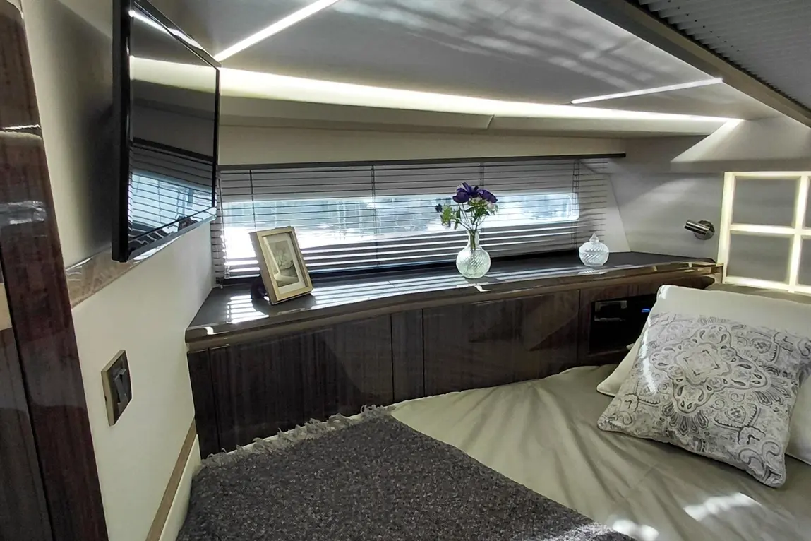 Luxurious bedroom interior featuring a TV, floral vase, decorative pillow, and ambient lighting, offering a modern aesthetic.